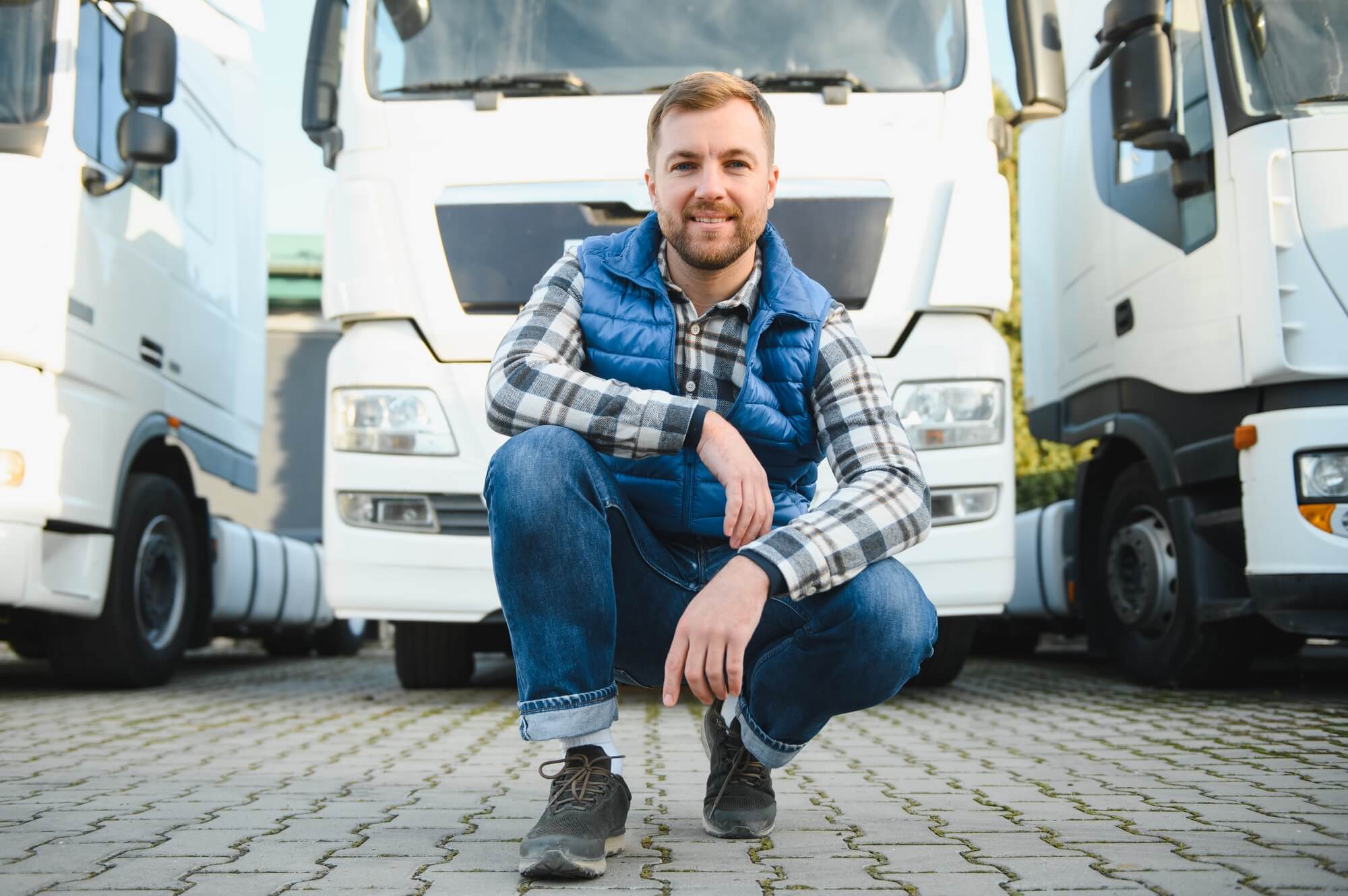 Freight transportation. A handsome truck driver stands on the background of a truck