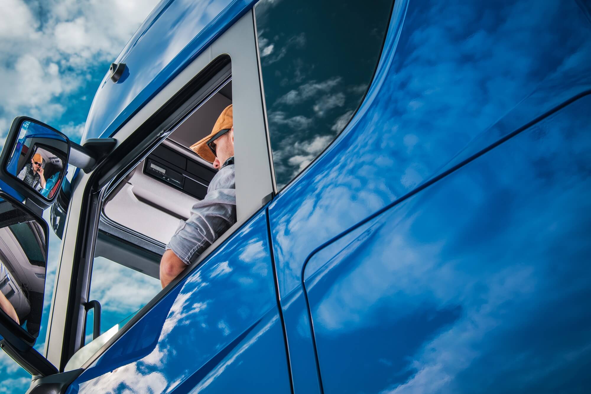 Truck Driver Sitting in Drivers Seat of a Blue Semi Truck